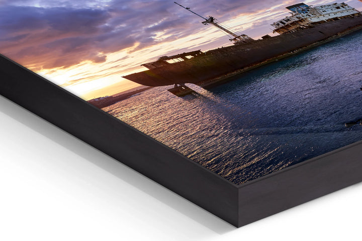 Wooden-framed photo print corner showing a dark ship silhouette on calm sea at sunset with dramatic purple and orange clouds. - 45 x 30cm / Photo hinter Acrylglas / Unframed