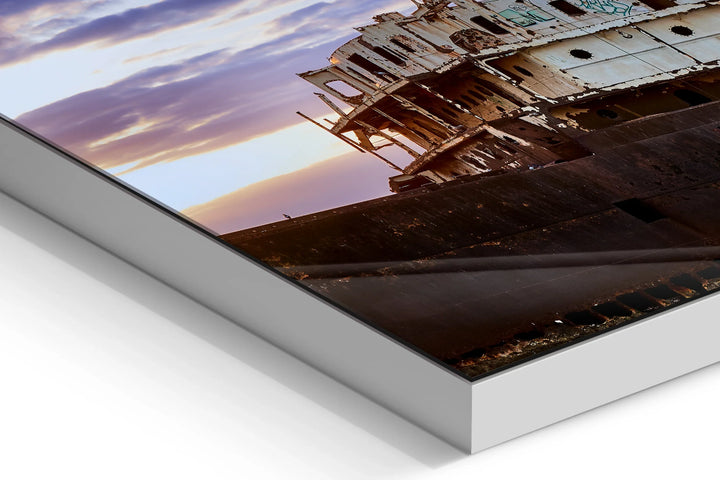 Rusting ghost ship wreck on a rocky shore under a purple and orange cloudy sky at dusk. - 45 x 30cm / Photo hinter Acrylglas / Unframed