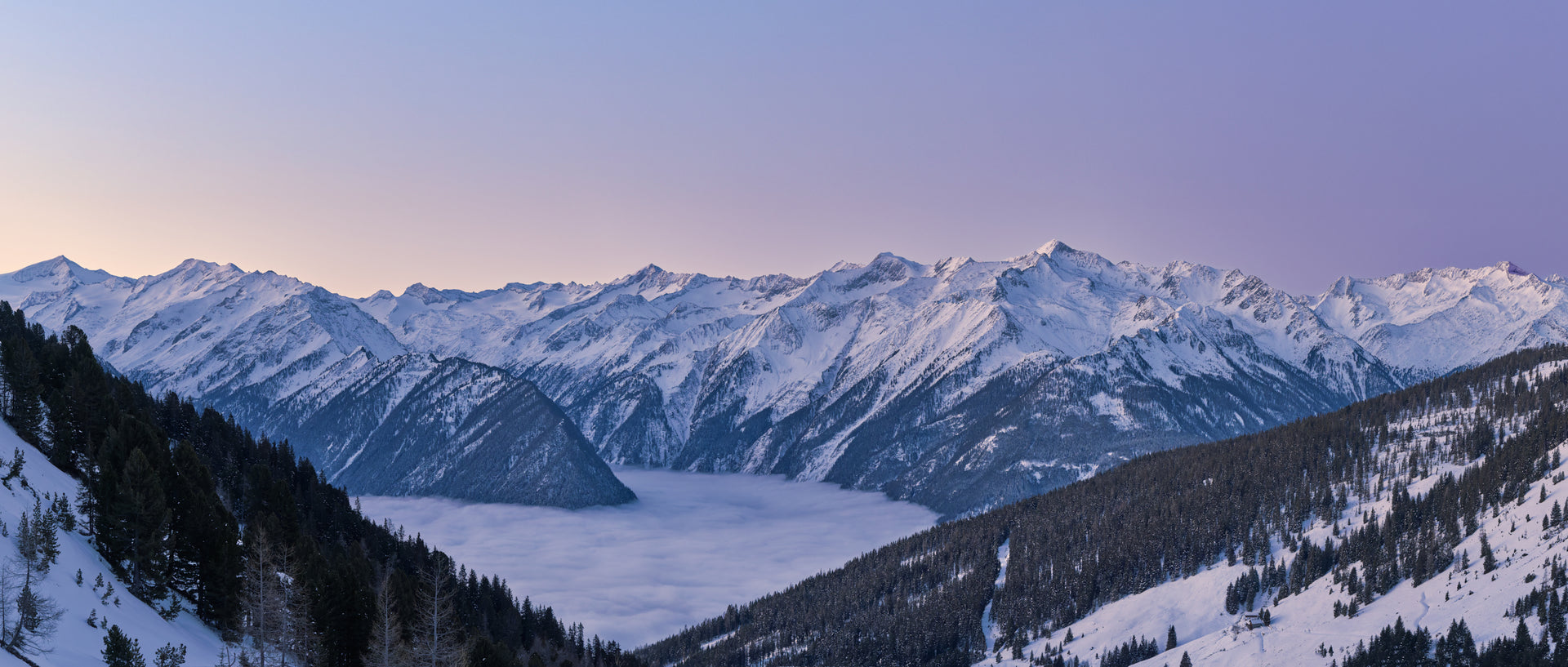 Snow-covered Hohe Tauern mountain range under soft blue hour sky with mist in valley below. - 90 x 38 cm / Photo hinter Acrylglas / Unframed
